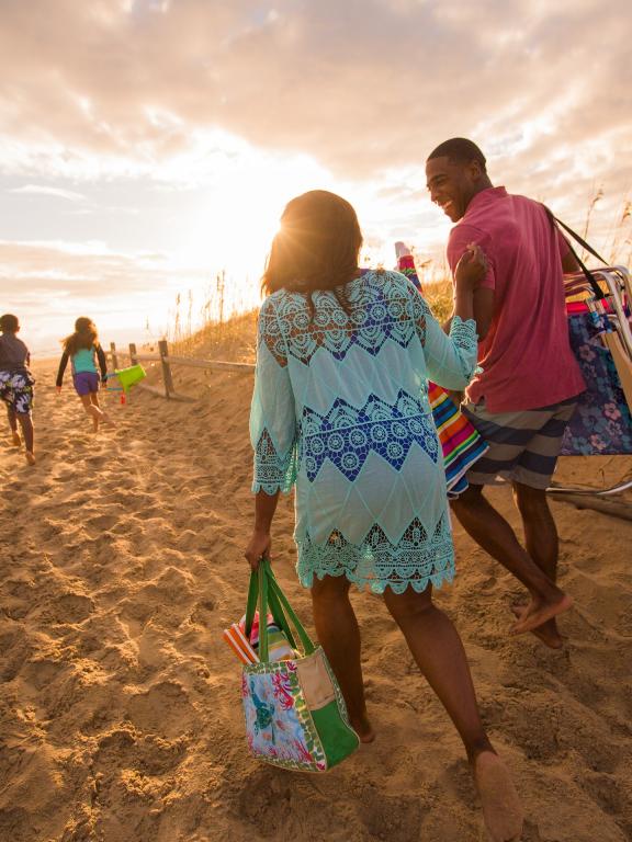 A family walking up a dune towards the sunset