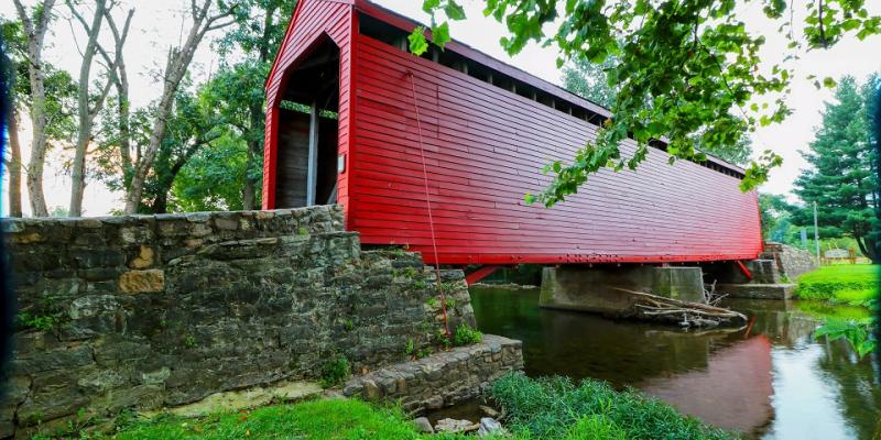 The bright red Roddy Road Covered Bridge spanning a creek near Thurmont, Maryland, USA