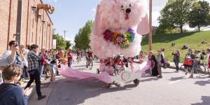 A kinetic poodle sculpture passes spectators